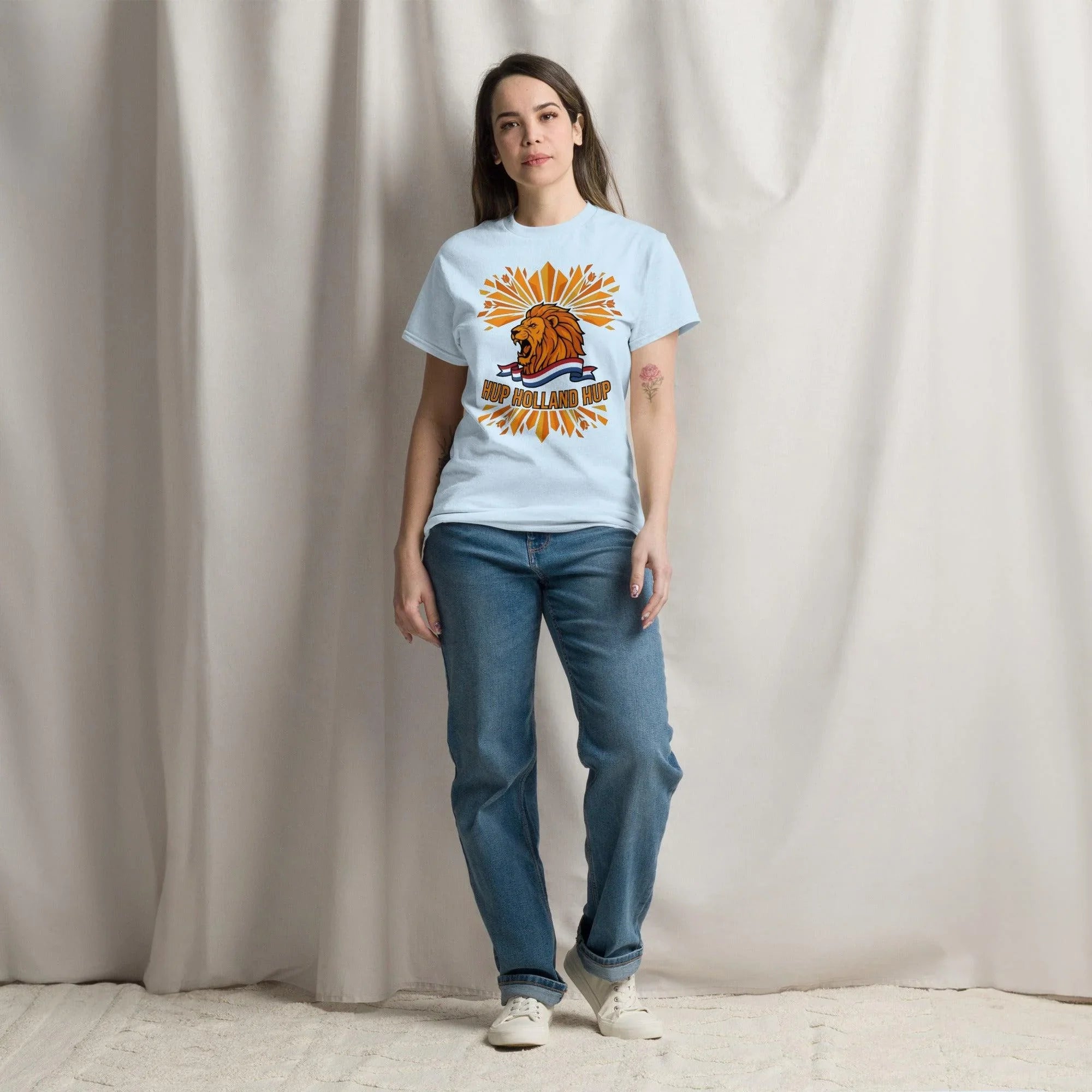 Woman wearing light blue 'Hup Holland Hup' t-shirt with lion graphic, perfect for football fans and sports apparel lovers.